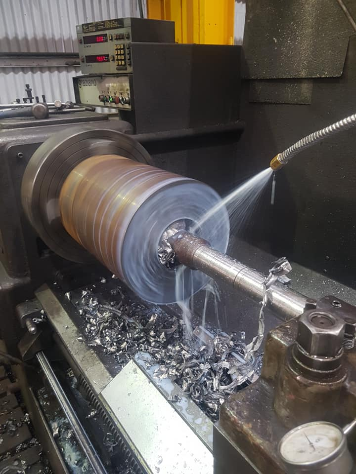 Steel shaft being turned on a lathe with coolant flowing in the Lavis workshop